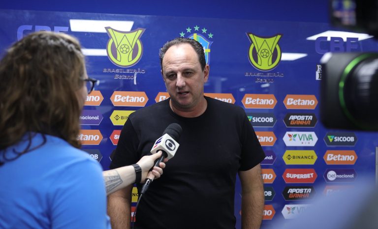 Rogério Ceni em entrevista para a Globo com placa de publicidade da série a atrás